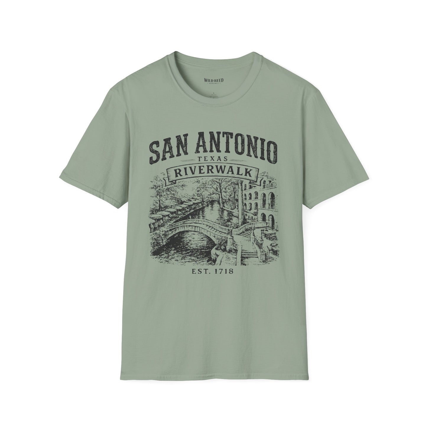A sage short-sleeve t-shirt with a dark gray graphic print on the front reading 'SAN ANTONIO RIVERWALK TEXAS EST. 1718' above an illustration of a river scene with a bridge.