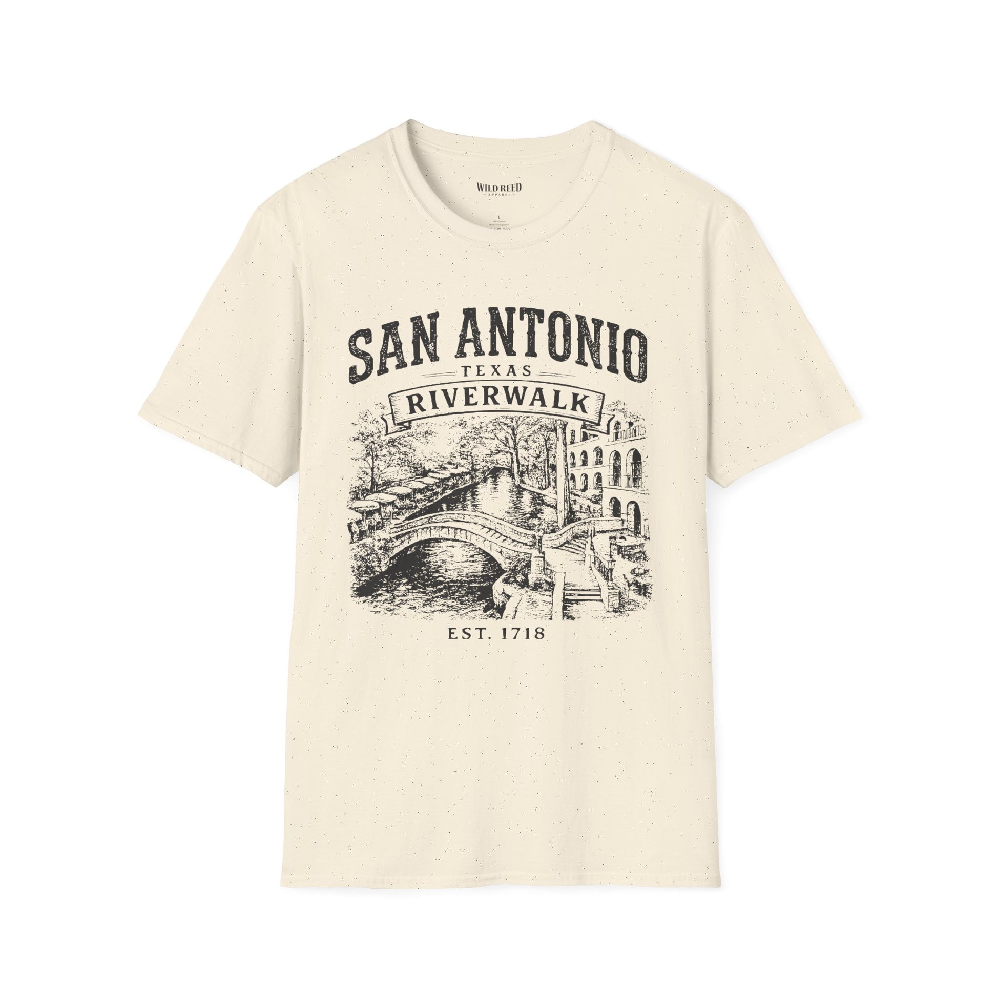 An off-white short-sleeve t-shirt with a black graphic print of San Antonio's Riverwalk featuring a bridge, canal, and buildings, with text reading 'SAN ANTONIO TEXAS RIVERWALK' and 'EST. 1718'.
