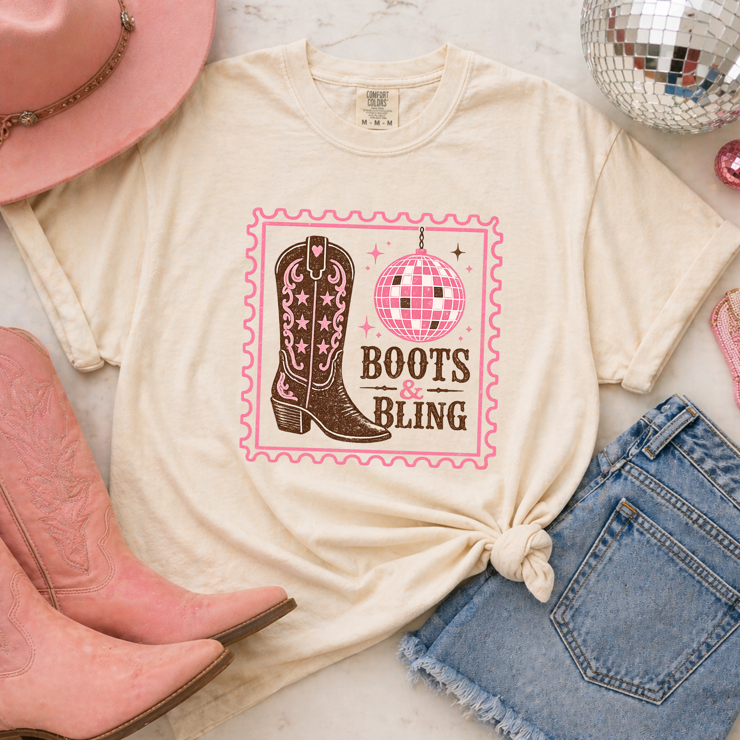 Boots and Bling shirt flat lay with pink boots disco ball and western accessories