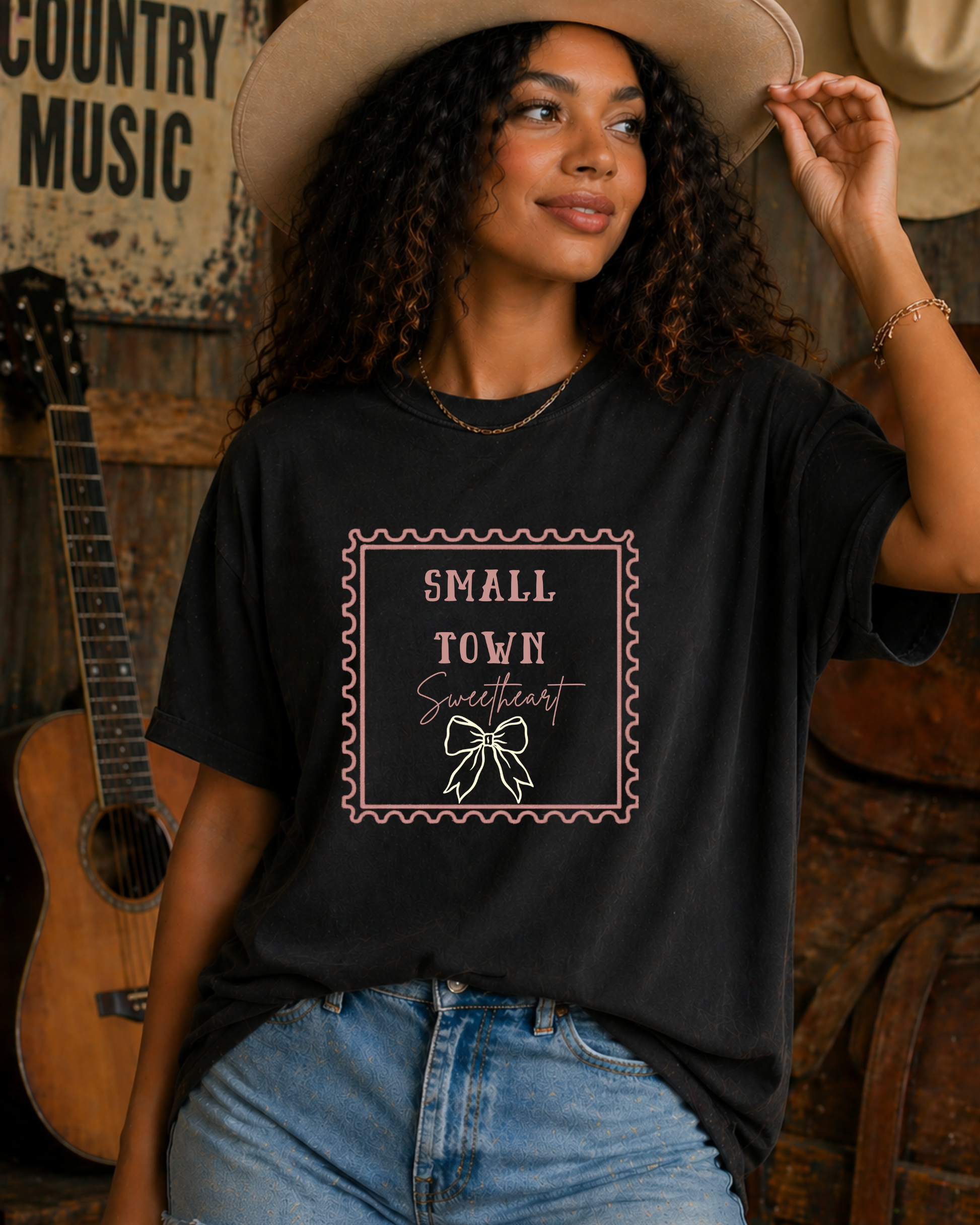 Woman wearing black Small Town Sweetheart western graphic tee holding cowboy hat