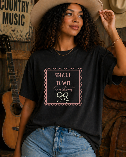 Woman wearing black Small Town Sweetheart western graphic tee holding cowboy hat