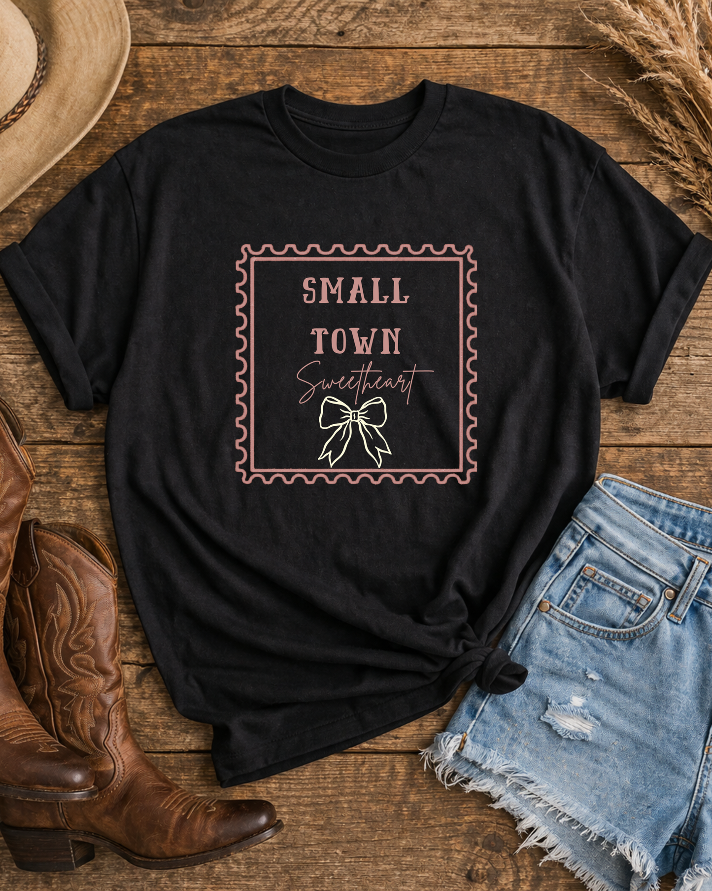 Black Small Town Sweetheart western bow graphic t-shirt flat lay with cowboy boots denim shorts and hat