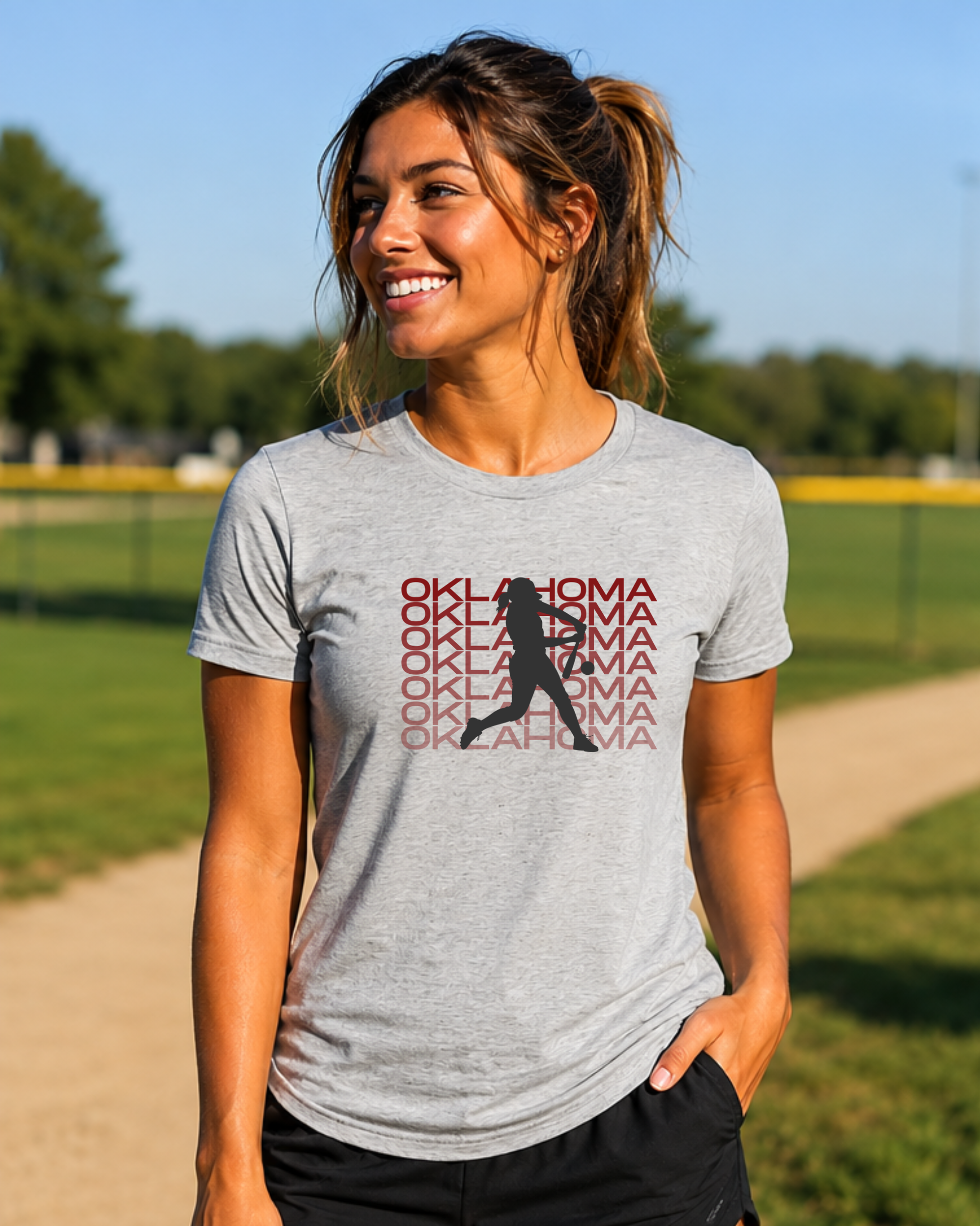 Woman wearing an Oklahoma softball graphic tee on athletic heather at a softball field