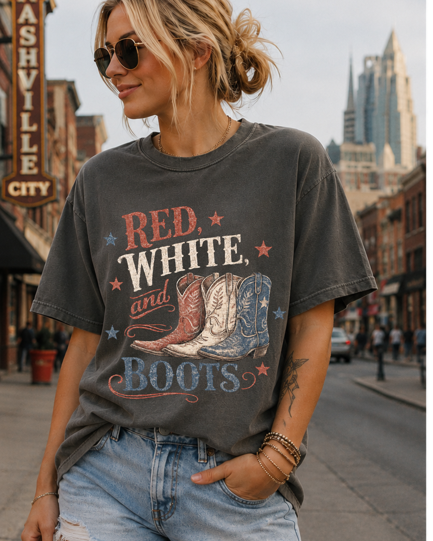 Woman wearing a vintage washed Red White and Boots western graphic tee featuring distressed patriotic cowboy boots and retro Americana typography.