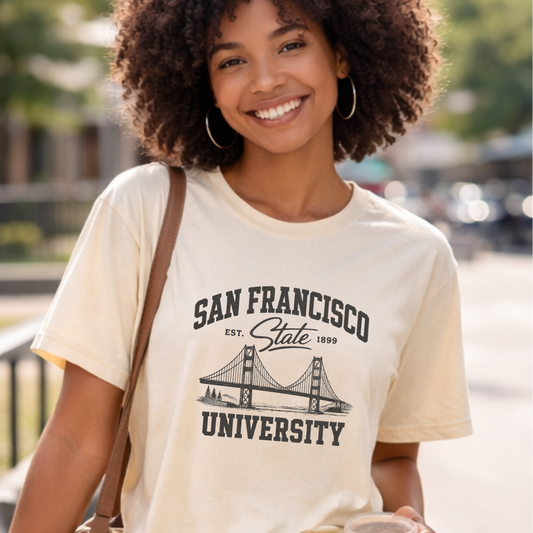 Woman wearing a neutral San Francisco State University graphic t-shirt featuring a vintage Golden Gate Bridge design while walking outdoors.
