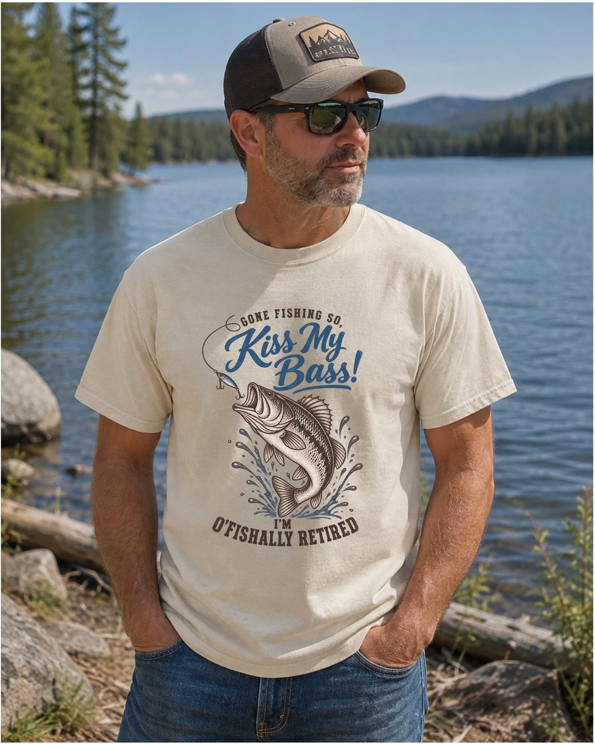 a man wearing a natural graphic t-shirt with a blue and brown fish design and the text 'Gone Fishing So, Kiss My Bass! I'm O'Fishally Retired