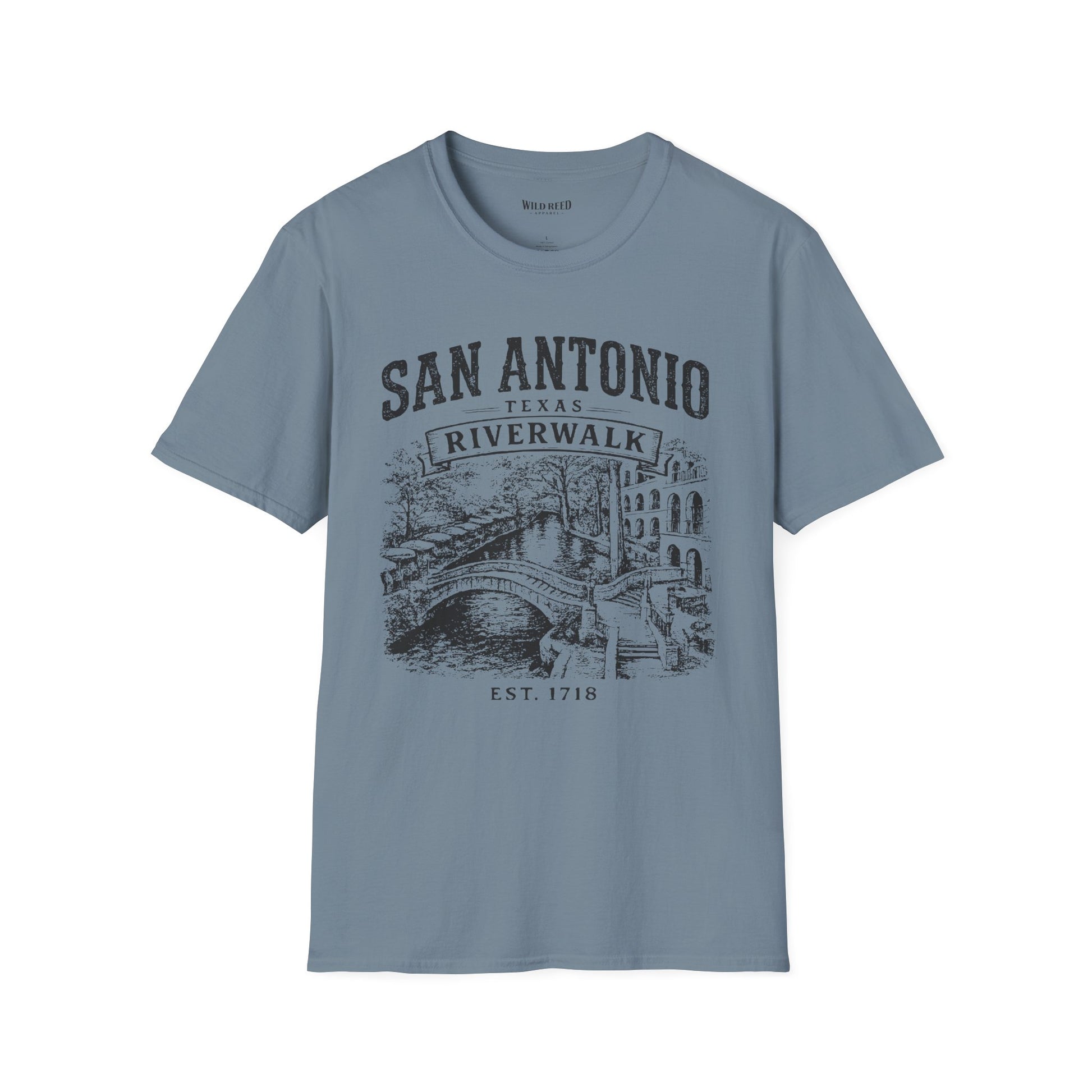 A stone blue crewneck t-shirt featuring a dark gray graphic print of the San Antonio Riverwalk with a bridge and buildings, displayed on a clean white background.