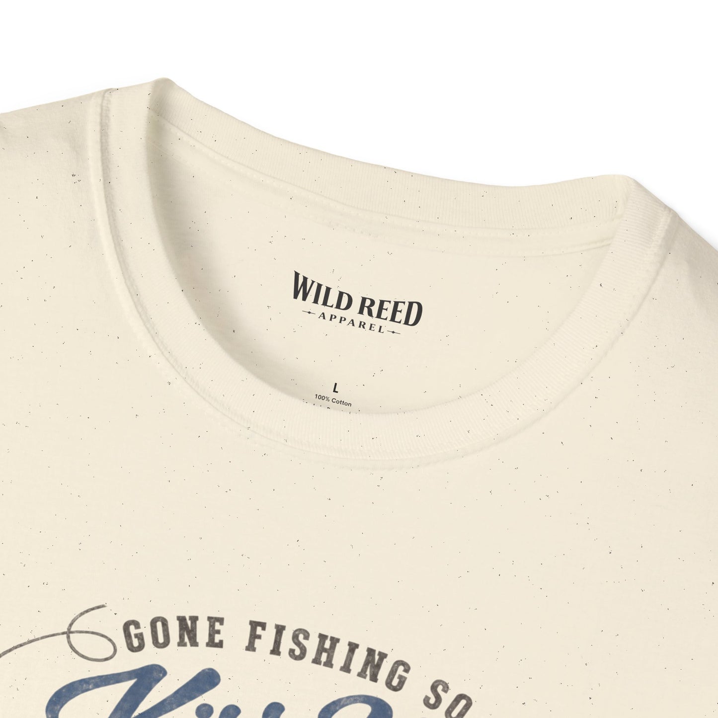 Close-up of a cream-colored t-shirt with a subtle speckled texture, showing the inner neck label 'WILD REED APPAREL' and the top of a graphic print that reads 'GONE FISHING SO'.